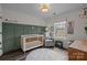 A charming Bedroom with a green accent wall, a crib, and a cozy armchair at 1710 Woodward Ave, Charlotte, NC 28206