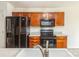 A kitchen with wooden cabinetry and black appliances; microwave, stove and refrigerator shown at 2019 W Laporte Dr, Charlotte, NC 28216