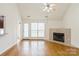 Cozy living room featuring hardwood floors, fireplace, ceiling fan, and bright windows at 2019 W Laporte Dr, Charlotte, NC 28216