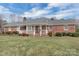 Inviting brick home featuring a welcoming covered front porch, classic red shutters, and well-maintained landscaping at 218 Countryside Rd, Kings Mountain, NC 28086