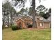 Single-story home featuring brick and tan siding, red shutters, and mature trees at 2517 Bushy Pine Ct, Charlotte, NC 28273