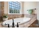 Bathroom featuring a deep soaking tub, tile surround, and a large window at 3815 10Th Ne St, Hickory, NC 28601