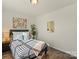 Brightly lit bedroom with a plant, mirror and warm wood floors and a bed with plush bedding at 5703 Eleanor Rigby Rd, Charlotte, NC 28278
