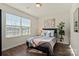Bright bedroom with a sunlit window, hardwood floors, and a comfy bed with decorative pillows and a potted plant at 5703 Eleanor Rigby Rd, Charlotte, NC 28278