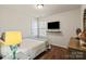 Comfortable bedroom featuring a mounted TV, wood floors, and a cozy bed with a lamp and bedside table at 5703 Eleanor Rigby Rd, Charlotte, NC 28278