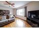 Cozy living room with hardwood floors, ceiling fan, a large window, and TV at 5743 Cherrycrest Ln, Charlotte, NC 28217
