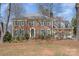 Two-story brick home with green shutters and a meticulously maintained lawn with budding plants at 8807 Thornbury Ln, Huntersville, NC 28078