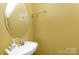 Small bathroom with white sink and chrome faucet, with a round mirror and tan walls at 10228 Seedling Ln, Charlotte, NC 28214