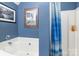 Blue tiled full bathroom featuring a tub, shower, and framed artwork at 10228 Seedling Ln, Charlotte, NC 28214