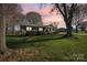 Brick home surrounded by mature trees and lush lawn at dusk provides tranquility at 108 Colonial Dr, Kings Mountain, NC 28086