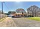 Charming brick ranch-style home with a detached garage, and spacious front yard on a sunny day at 1356 Ford Dr, Lowell, NC 28098