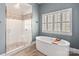 Modern bathroom featuring a glass shower, soaking tub, and a window with natural light at 2007 Fernhurst Ter, Matthews, NC 28104