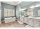 Well-lit bathroom featuring a soaking tub, dual sinks, and stylish vanities with ample counter space at 2007 Fernhurst Ter, Matthews, NC 28104