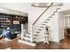 Elegant foyer with hardwood floors, curved staircase, and view into a study with built in bookcases at 2007 Fernhurst Ter, Matthews, NC 28104