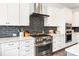 Modern kitchen featuring a stainless steel range, white cabinetry, and black backsplash at 2007 Fernhurst Ter, Matthews, NC 28104