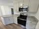 Stylish kitchen featuring stainless steel range, microwave, granite countertops and white cabinets with black hardware at 2190 Pacer Rd, Lancaster, SC 29720