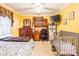 Bedroom with yellow walls, ceiling fan, TV, dresser, desk, and grey crib at 2455 Wellridge Rd, Chester, SC 29706