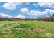 A sprawling grassy field is bathed in sunlight under a partly cloudy blue sky at 2455 Wellridge Rd, Chester, SC 29706