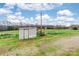 An outbuilding and fenced pasture area sit beneath a blue sky with bright white clouds at 2455 Wellridge Rd, Chester, SC 29706