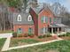 Elegant brick home with a covered front porch, complemented by lush landscaping and a well-maintained lawn at 2538 Cherry Bark Oak Ct, Gastonia, NC 28056