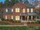 Beautiful brick home featuring a cozy covered porch, lush landscaping and warm lighting, a welcoming retreat at 2538 Cherry Bark Oak Ct, Gastonia, NC 28056