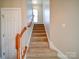 Carpeted stairway with wooden handrail and natural light from the window above at 2538 Cherry Bark Oak Ct, Gastonia, NC 28056