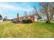 Backyard view of a brick home, deck, trimmed greenery, and an attached garage on a grassy lot at 30 Hillsboro Rd, Taylorsville, NC 28681