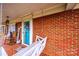Charming front porch with a swing, rocking chair, and welcome decor, all framed by classic red brick and trim at 30 Hillsboro Rd, Taylorsville, NC 28681