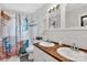 Bright bathroom featuring double sinks with wood countertop and shower and tub combination with decorative curtain at 3036 Marlowe Ave, Charlotte, NC 28208