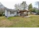 Backyard view featuring a covered deck, a well-maintained lawn, and mature trees at 3901 Durham Ln, Charlotte, NC 28269