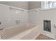 Bathroom with a white tiled wall surrounding a bathtub and small window letting in natural light at 407 Pinecroft Ln, Spencer, NC 28159