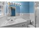 White-tiled bathroom with blue walls, a toilet, large sink with a mirror, and shower stall at 407 Pinecroft Ln, Spencer, NC 28159