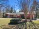 Traditional brick home featuring a well-maintained lawn, mature trees, shrubbery and a handicap accessible ramp at 407 Pinecroft Ln, Spencer, NC 28159