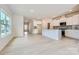 Open-concept kitchen with white cabinets, gray backsplash, stainless appliances, and light wood floors at 4465 Dusty Orchard Rd, Kannapolis, NC 28081