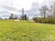 A sprawling grassy backyard backs up to a house, powerlines, and other foliage at 5609 Morgan Mill Rd, Monroe, NC 28110