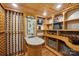 Wine cellar complete with custom shelving, stone accents, granite topped island, and wood ceiling at 653 Buckleigh Nw Ct, Concord, NC 28027