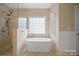 Bright bathroom featuring a freestanding soaking tub and a glass shower with beige tile at 722 Fairway Point Dr, Fort Mill, SC 29708