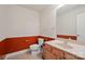 Half bathroom with toilet, sink, wood cabinets, and rust-colored accent wall at 722 Fairway Point Dr, Fort Mill, SC 29708