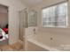 Bathroom showcasing a large bathtub with a shower and a large window at 8527 Conner Ridge Ln, Charlotte, NC 28269
