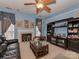 Cozy living room featuring a fireplace, ceiling fan, dark wood shelving, and comfortable seating, set against soft blue walls at 8527 Conner Ridge Ln, Charlotte, NC 28269