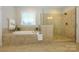 Bright bathroom with soaking tub, glass shower and neutral tile at 8941 Vickery Ln, Harrisburg, NC 28075