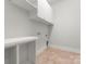 Clean, white laundry room with storage shelving, cabinets and tile flooring at 917 Herrons Ferry Rd, Rock Hill, SC 29730