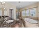 Bright bathroom featuring double sink vanity, soaking tub, tiled shower, and linen closet at 10129 Loch Lomond Dr, Charlotte, NC 28278