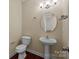 A well-lit powder room featuring a pedestal sink, a white toilet, and modern fixtures, all on a hardwood floor at 10129 Loch Lomond Dr, Charlotte, NC 28278