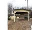 A view of the covered parking area and some sheds sits against a backdrop of bare trees on a cloudy day at 1140 Mt Vernon Rd, Woodleaf, NC 27054