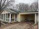 The home's exterior shows yellow siding, a metal roof, and a covered parking area next to a bare tree at 1140 Mt Vernon Rd, Woodleaf, NC 27054