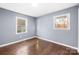 Well lit bedroom featuring hardwood floors, two windows with natural light, and gray painted walls at 1203 Northwoods Dr, Kings Mountain, NC 28086