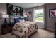 This bedroom has carpet, a window, bedside table, a bed with football themed bedding and sports decorations at 1240 Cottage Green Dr # 0132, Monroe, NC 28112