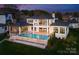 Modern home showcasing a stunning infinity pool and spa overlooking lush greenery and a covered patio at 18601 Bluff Point Rd, Cornelius, NC 28031
