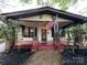 Charming bungalow featuring an inviting front porch, brick columns, and an American flag at 211 W 6Th Ave, Gastonia, NC 28052